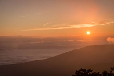 Scenic view of silhouette mountains against orange sky