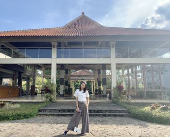 Woman standing by building against sky