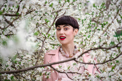 Portrait of a smiling young woman sitting on cherry tree