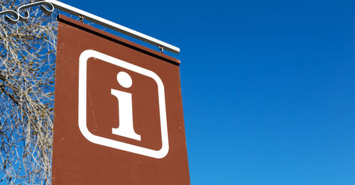 Low angle view of sign against clear blue sky