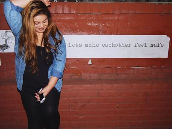 Beautiful young woman standing against wall