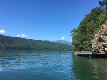 Scenic view of lake and mountains against blue sky