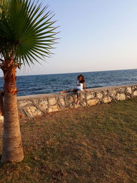 Woman with umbrella on beach against sky