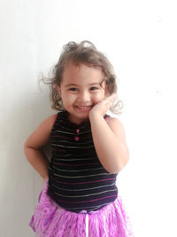 Portrait of a smiling girl standing against wall