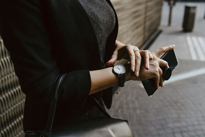 Midsection of businesswoman checking time on wristwatch
