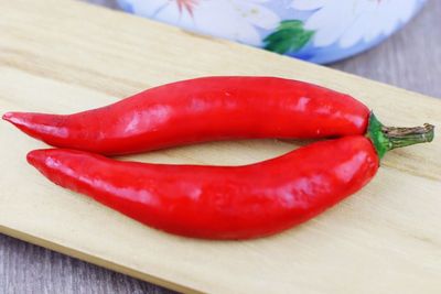 Close-up of red chili peppers on cutting board over table