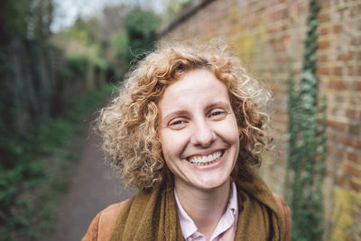 Portrait of smiling woman against brick wall