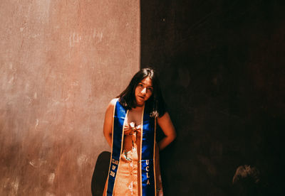 Portrait of woman standing against wall