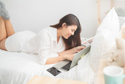 Young woman using laptop on bed