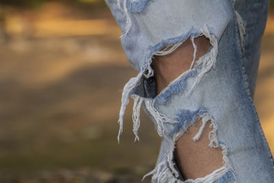 Midsection of person wearing torn jeans