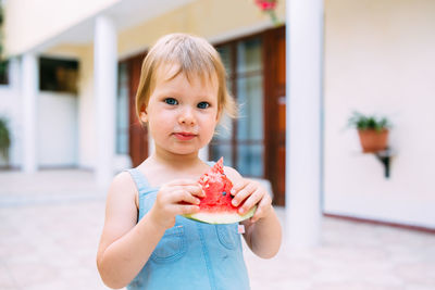 Little cute cheerful girl eating a slice of watermelon close up.