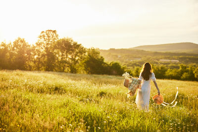 Rear view of woman standing on grassy field against sky