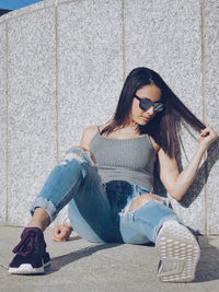Portrait of young woman sitting on wall