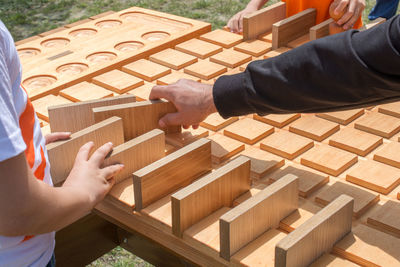 Cropped hand of man arranging blocks with family on field