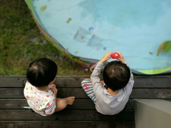 Rear view of siblings sitting at porch