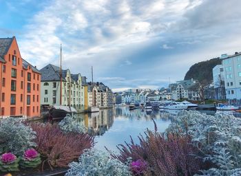 Buildings by river against sky