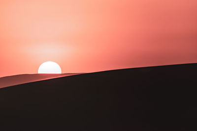 Silhouette built structure against orange sky