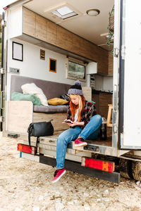 Traveling female sitting in truck and messaging on mobile phone