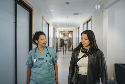 Female doctor discussing with patient while walking in corridor of hospital