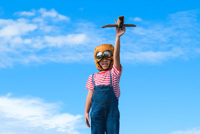 Low angle view of man with arms outstretched against sky