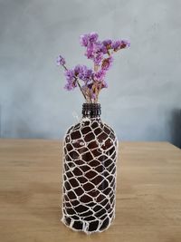 Close-up of purple flower vase on table against wall