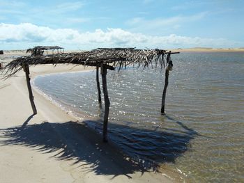 Wooden posts on beach against sky