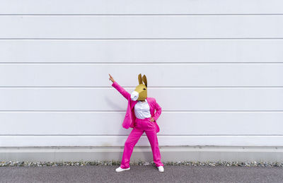 Full length of woman standing against pink wall