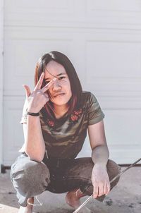 Young woman sitting against wall