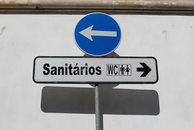 Restroom sign with arrow symbol against wall