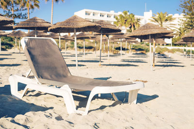Empty chairs on sand at beach