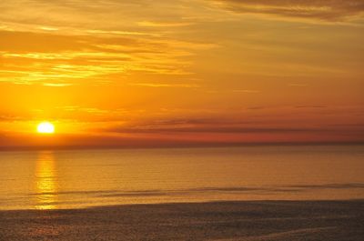 Scenic view of sea against dramatic sky during sunset