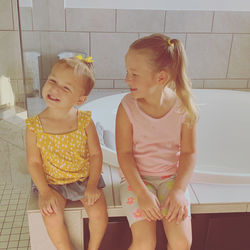 Cute sisters sitting in bathroom