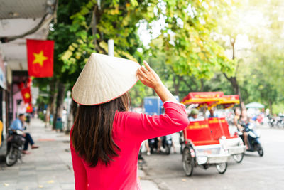 Rear view of woman holding umbrella while standing in park