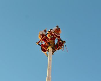 Low angle view of papantla flyers against clear blue sky