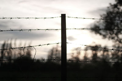 Low angle view of silhouette fence against sky