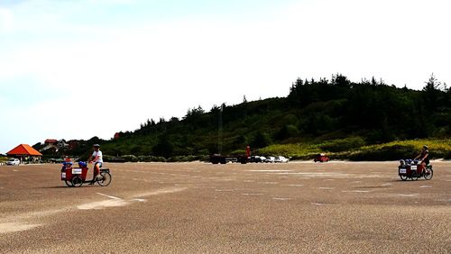 People riding motorcycle on road against sky