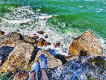 Low section of person on rock in sea