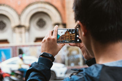 Rear view of man photographing with mobile phone