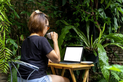 Full length of woman sitting on mobile phone