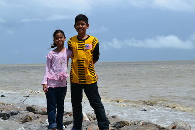 Two siblings posing by the sea while on vacation