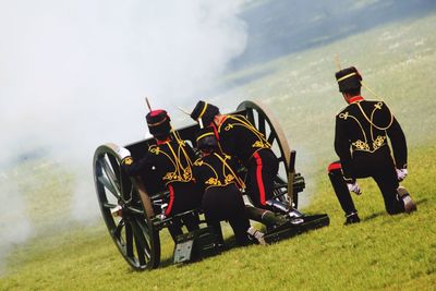 Rear view of army soldiers with metallic wheels on grassy field