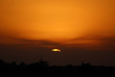 Silhouette trees against orange sky