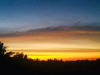 Silhouette trees against dramatic sky during sunset