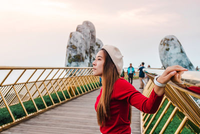 Woman standing on footbridge against sky