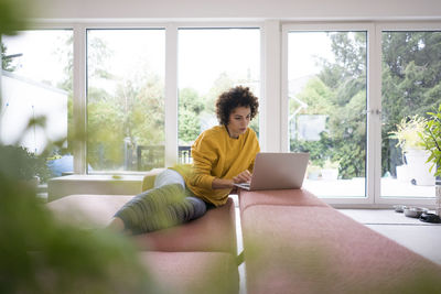 Woman using laptop on couch at home