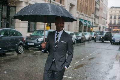 Businessman with umbrella walking on road