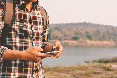 Man using smart phone by river