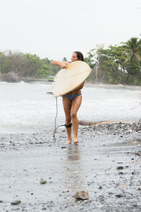 Woman with surfboard walking at beach