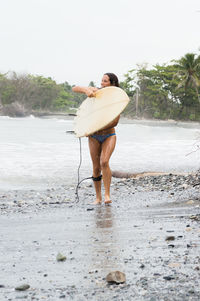 Rear view of man with umbrella walking on wet shore