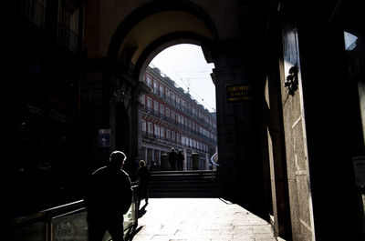 Rear view of people walking on street amidst buildings in city